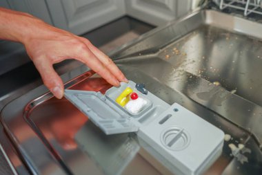 Bulaşık makinesi tabletini kirli bulaşık makinesine koyan kişi. Bulaşık..