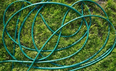 Çimlerin üzerinde bahçe hortumu. Bahçe teması. Bahçe çimenleri ve hortum arka planı. Bahçe deseni.