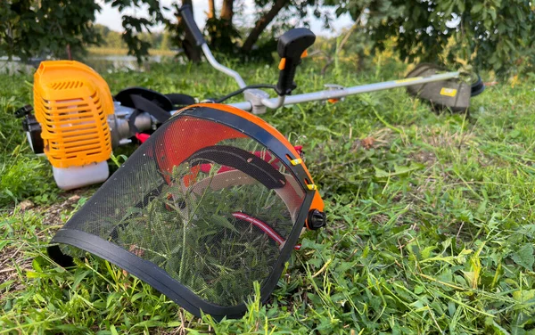 Çimleri biçme makinesiyle biçmek. Çim biçme için koruyucu vizör. Koruyucu giysilerle çimleri biçen sonbaharlar.