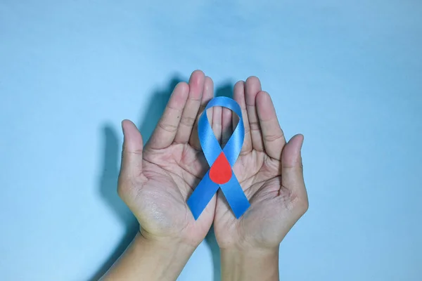 顶部视图蓝带意识到与红血滴在人的手隔离在蓝色背景 11月14日世界糖尿病日复制空间 — 图库照片