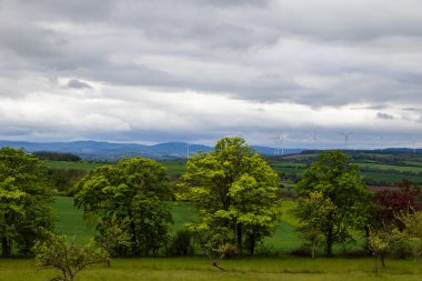 Tepe ve rüzgar jeneratörleriyle gri bahar günü manzarası