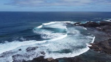 Güçlü dalgalar rüzgarlı bir öğleden sonra kayalık kıyı şeridine çarpar. Yüksek kalite 4K görüntü