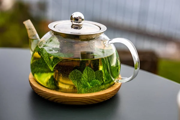 在户外的桌子上坐着一壶芬芳的薄荷茶 这是与健康饮食完美搭配的茶壶 — 图库照片