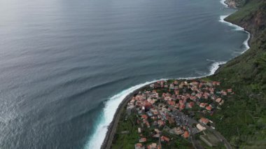 Madeira 'daki büyüleyici bir sahil köyünün üzerinde nefes kesici bir insansız hava aracı uçuşu deneyimi. Okyanuslar dramatik manzaraya büyük dalgalar eklenir..