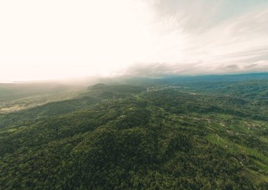Arkasında güzel tepeler olan kırsal bölgede akşam güneşinin hava manzarası.