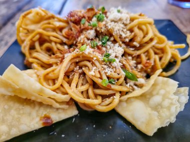 Kızarmış şehriye, ahşap bir masada, siyah bir tabakta servis edilir.