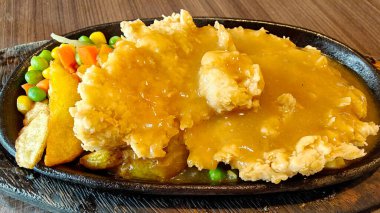 Kızarmış patates kızartması ve siyah ahşap tabakta sebzeli kızarmış tavuk bifteği.