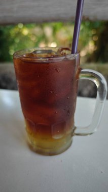 Cam fincanda buzlu çay, bulanık arka plan.