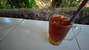 Cam fincanda buzlu çay, bulanık arka plan.