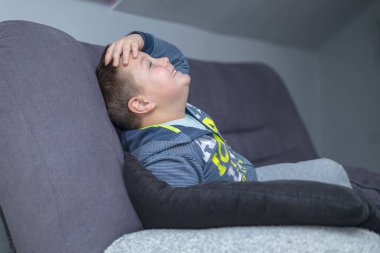 a boy sits, holds his head and laughs sarcastically because he failed to complete a mission in a video game. honest emotion of a boy playing a video game