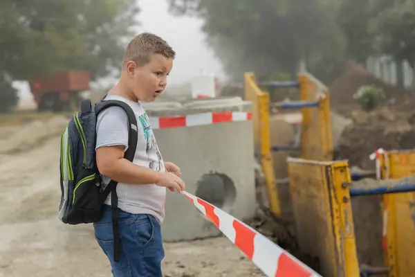 danger to students. a school boy comes across an excavation due to sewer digging works.the danger of going to school independently.construction works. warning and danger for children going to school