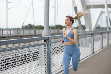 Köprüde koşan güzel, genç bir kadın.