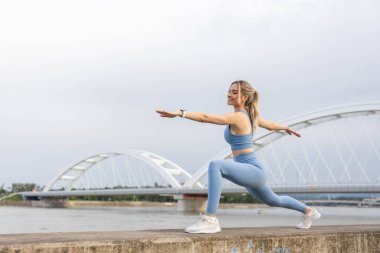  Spor elbiseli genç bir kadın dışarıda idmandan sonra esniyor.