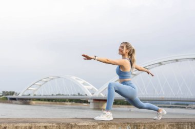  Spor elbiseli genç bir kadın dışarıda idmandan sonra esniyor.