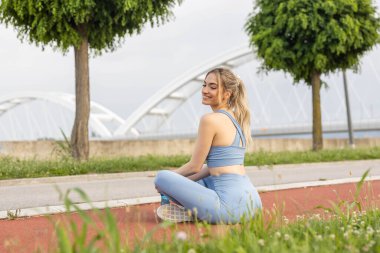 Şehirdeki koşu pistinde dinlenen genç ve güzel bir kadının portresi.