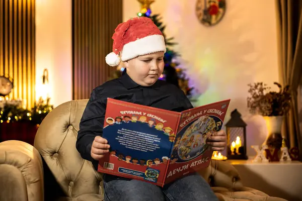Noel Baba şapkası takan genç bir çocuk, yumuşak, parıldayan bir Noel ağacının yanında uzanmış, huzurlu ve neşeli bir neşe atmosferi yaratıyor..