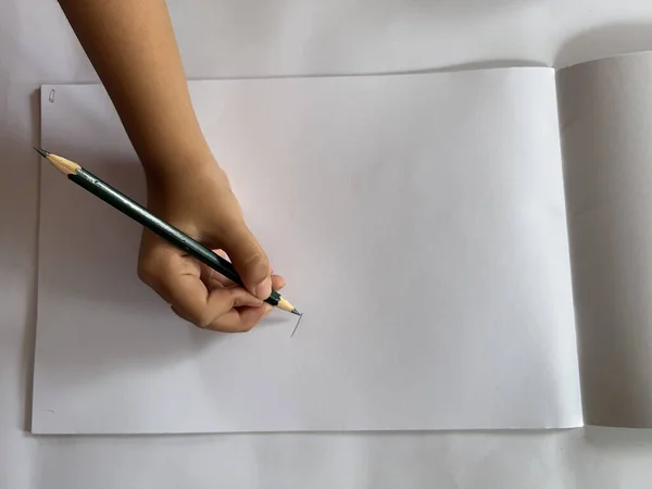 Elinde beyaz bir bardak çay ve defterinde kalem olan bir adamın elleri.