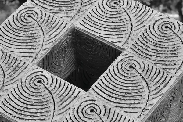 Iron cube decoration in a garden, black and white image.