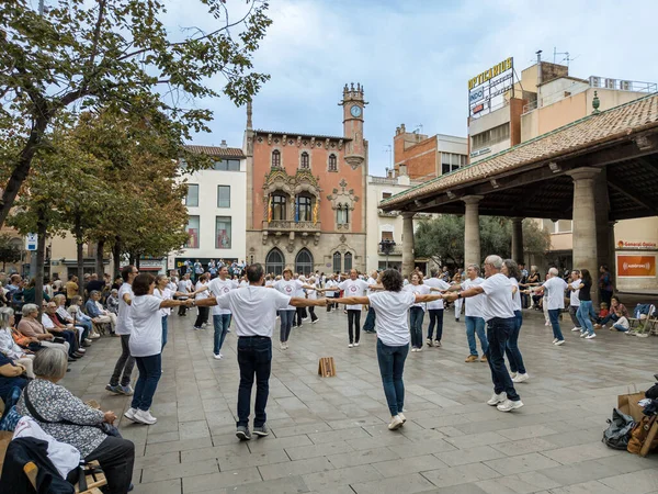 Granollers, Katalonya, İspanya; 10.22.2022: Granollers 'dan Sardanista grubu arka planda dinleyici kitlesi ve müzik çalan bir orkestra ile Granollers' ın veranda meydanında dans ediyor