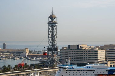 Barselona teleferiği ön planda, limana iniyor ve yolcu gemilerine demir atıyor.