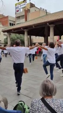 Granollers, Katalonya, İspanya; 10.22.2022: Granollers 'ın veranda meydanında dans eden sardancı grubun videosunu arka planda dinleyici kitlesi ve müzik çalan bir orkestra eşliğinde dikey taşımak