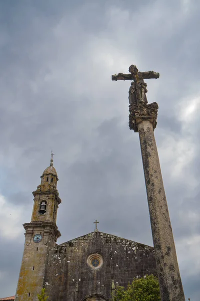 stock image View from below of the church of Rianxo and the statue of Jesus Christ with the cloudy sky in the background