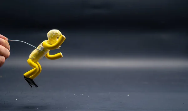 停止跳跃的过程 跳啊人的手拿着一根铝丝 上面挂着一个黄色的模型糊状的人物形象 动画的12个原则 — 图库照片