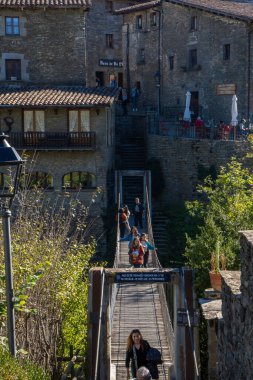 İnsanlar Rupit 'in asma köprüsünü ve arkadaki eski evleri geçiyor.