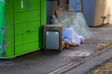 Çantaları, camları ve yerde eski bir televizyonu olan bir çöp kutusu.