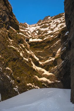 Totally snowy road between the mountains towards the Kvernufoss waterfall and a gorge with snowy areas and illuminated with the sunrise sun illuminating the snowy peaks of Iceland