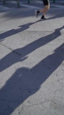 Spor ayakkabıları ve bir çok koşucunun bacakları şafağın ilk ışıklarıyla uzamış gölgeli asfalt bir sokakta maratonun önünde koşup ısınıyor.