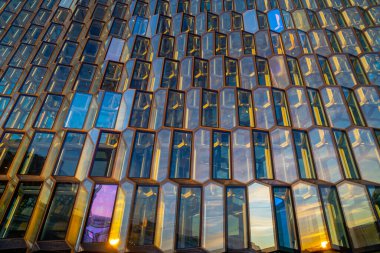 Avangart mimari yapısının ayrıntıları ve Harpa konser binasının ön cephesi ve cam kapıları ve sabah güneşiyle aydınlatılan konferans merkezi, ışığını ve renklerini yansıtıyor ve arı kovanını taklit ediyor. Orası bir ev.