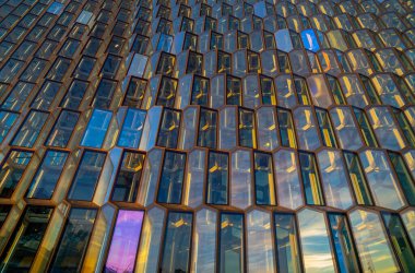 Avangart mimari yapısının ayrıntıları ve Harpa konser binasının ön cephesi ve cam kapıları ve sabah güneşiyle aydınlatılan konferans merkezi, ışığını ve renklerini yansıtıyor ve arı kovanını taklit ediyor. Orası bir ev.