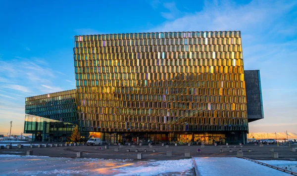 stock image Harpa building reykjavik concert and conference center with all the facade of modular glass windows illuminated by the morning sun and the surroundings with snow. It is home to the Icelandic Symphony