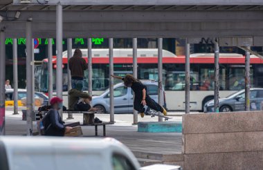 Aksiyon eğlencesi içinde atlayan, sokak parkında kaykay üzerinde poz veren ve numaralar yapan genç şehir patencisi arkadaşları alternatif şehir kıyafetlerini giymiş beton bir bankta dinleniyorlardı.