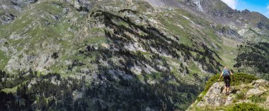 Woman hiker on top of a mountain watching the mountainous landscape of the high mountain pyrenees