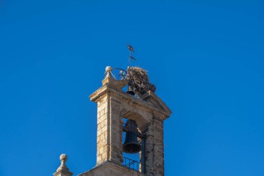 Leylek yuvası, çan kulesinin tepesine dallar ve Salamanca 'nın eski katedralinin açık mavi gökyüzünün altında küçük bir çanıyla tünemiş ve inşa edilmişti.