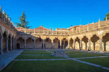 Salamanca Üniversitesi manastırı çimenlerle ve akşam güneşinin ışığıyla güzelce aydınlatılmış bir taş kuyusuyla koridorların duvarlarına kemer ve sütunların gölgesini seriyor..