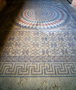 Mavi ve kırmızı romboidal figürlere sahip Roma mozaiğinin arkeolojik kalıntıları renkli süslemeler ve zenginliklerle sınırlandırılmış bir dairenin fraktal yapısını oluşturuyor. Merida 'daki Mitreo Roma Evi.