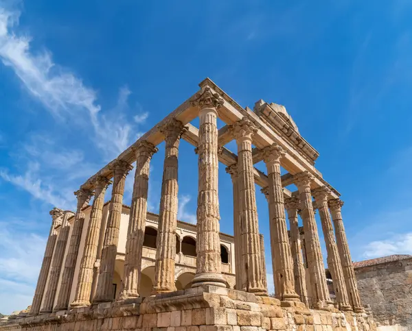 Temiz mavi gökyüzünün altında, Korint tarzı mermer sütunlarla, Diana Tapınağı 'nın sol tarafından tam görüş. Merida. Badajoz ili, Extremadura, İspanya. Dikey bayrak.