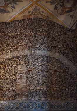 İnsan kemikleri ve kafataslarından oluşan bir duvar kemer şeklinde bir tasarım ve Kemik Şapeli 'ndeki dini alegorik tablolarla dolu bir tavan oluşturuyor. Evora, Portekiz.