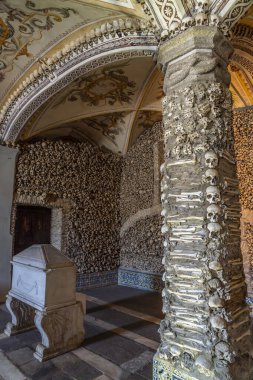 İnsan kemikleri ve kafatasları ile süslenmiş sütun, dini alegorik tablolarla dolu kubbeli tavan ve Kemikler Şapeli 'nin mermer mezarı. Evora, Portekiz.