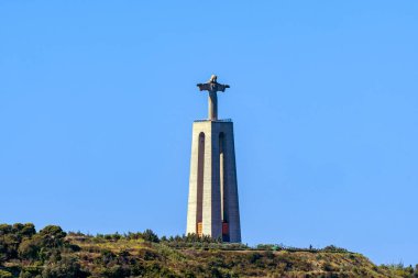 İsa 'nın anıtsal taş heykeli Lizbon Kralı Almada' nın (Christus Heykeli Lissabon) panoramik görüntüsü, Almada 'nın Kutsal Kalbi' ne adanmış bir mabet. Açık mavi gökyüzü.