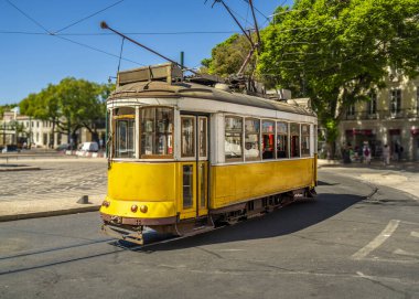 Ünlü ve tipik sarı Portekiz tramvayı, güzelce dekore edilmiş ve korunmuş, Portekiz 'de tipik bir Lizbon caddesinin kavşağında koşuyor..