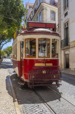 Ünlü ve tipik eski Portekiz tramvayı, güzel dekore edilmiş, Lizbon 'daki Alfama Mahallesi' nin tipik bir kaldırım taşı sokağında dolaşıyordu..