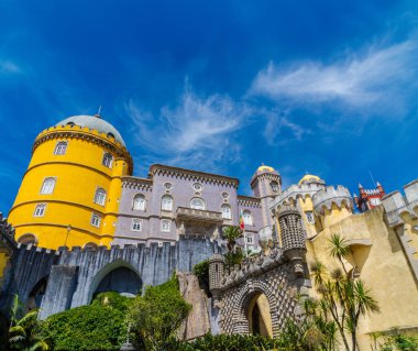 Sarı, kırmızı ve mozaik renklerden oluşan Pena Sarayı 'nın giriş yolunun dış ve geniş manzarası. Sintra 'da, güneşli mavi gökyüzünün altında. Portekiz.