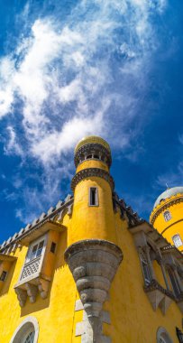 Orta çağ pencere açıklığı olan bir muharebenin düşük açılı görüntüsü ve üst kısmı Pena Palace 'ın sarı mozaik kubbesiyle sütunlarla tamamlanmış. Sintra 'da, güneşli mavi gökyüzünün altında. Portekiz.