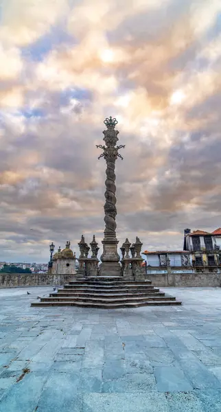 The ornate carved column of the Porto picotade or pelourinho stone monument with its stone stairs in the square in front of the Terreiro da Se Cathedral, Porto, Portugal.