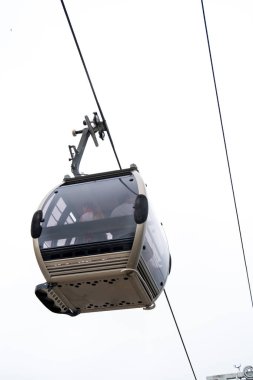 Porto 'da bulutlu beyaz bir gökyüzünün altında çelik bir kabloyla asılı duran Vila Nova de Gaia teleferik gondolunun altından bir görüntü.