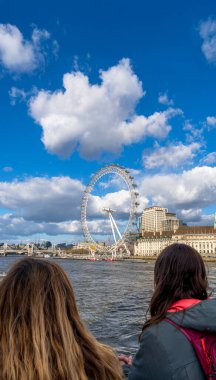 Lezbiyen bir çift Thames Nehri 'ndeki bir feribottan bakıyor ve düşünüyor. Önlerindeki Londra Gözü dönme dolabı..